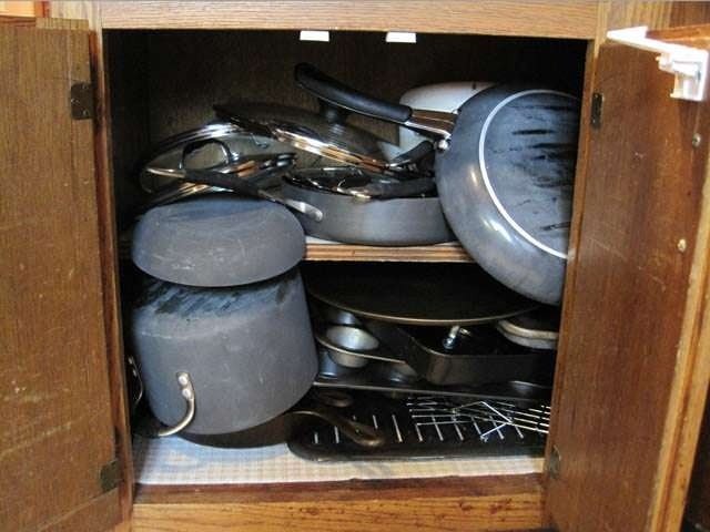 Picture showing overloaded cupboard with pots and pans with handles